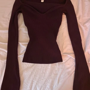 Vinröd V ringad tröja med utsvängda ärmar - . Tröjan har en tight passform och är tillverkad i stretchigt material som framhäver figuren. .