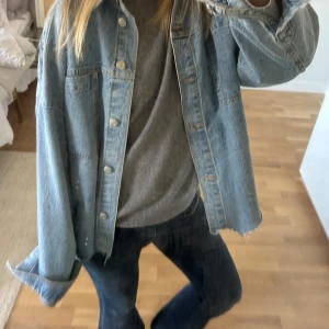 Blå jeansjacka - Snygg blå jeansjacka med knappar framtill. Jackan har en avslappnad passform och långa ärmar. 