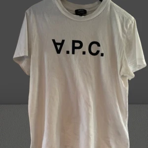 Vit t-shirt från A.P.C. - Säljer en stilren vit t-shirt från A.P.C. med svart logotyp på bröstet. T-shirten har en klassisk rund hals och korta ärmar. Perfekt för en minimalistisk look. NYPRIS 1200kr från NK
