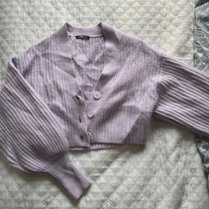Ljuslila ribbad kofta - Säljer en söt ljuslila kofta. Den är ribbad och croppad med knappar framtill. Perfekt för lager-på-lager-stil eller som ett statement-plagg i garderoben. 💜 använd 1-2 gånger bara🦋
