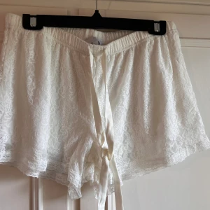 Vita spets shorts från Isabella - Säljer ett par vita pyjamasshorts i spets från Isabella. De har en elastisk midja och ett dekorativt knytband framtill. Oanvända.