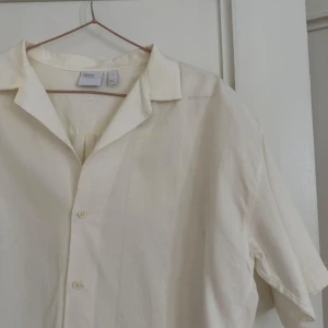 Vit kortärmad skjorta från ASOS - Säljer en stilren vit kortärmad skjorta från ASOS i 100% bomull. Skjortan har en klassisk krage och knappar framtill. Perfekt för en avslappnad och snygg look. Oversized 