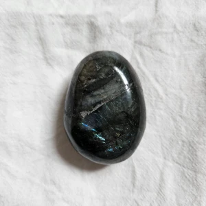 Labradorit sten, kristall  - Säljer en polerad labradorit med vackra blå och gröna skiftningar. Stenen är ovalformad och ca 6 cm lång.