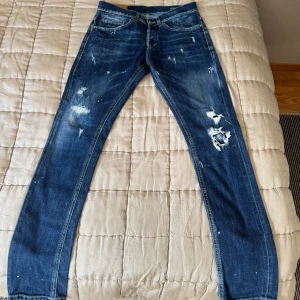 Blå Dondup ”George” skinny fit - Säljer ett par blå dondup george skinny för jeans med slitningar och färgstänk för en cool look
