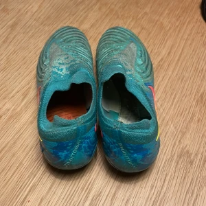 Nike Phantom fotbollsskor i turkos - Säljer ett par Nike Phantom fotbollsskor i turkos med blå och orange detaljer. Skorna är i okej skick men jag har tagit ut snörerna.Skriv vid funderingar!