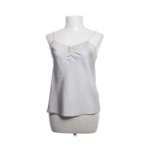 Vit linnetopp med spets från BikBok - Säljer en söt vit linnetopp från BikBok med tunna axelband och dekorativ spets upptill. Toppen har små knappar framtill och är tillverkad i ett glansigt material som känns lyxigt. Perfekt för varma dagar eller som layering-plagg.