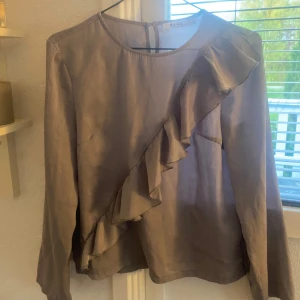 Blus med volanger  - Säljer en lila aktig blus med volang i storlek 34, tröjan är som S och M! Tröjan är ifrån NA-KD och i mycket bra skick! Säljer den för 70kr + frakt!