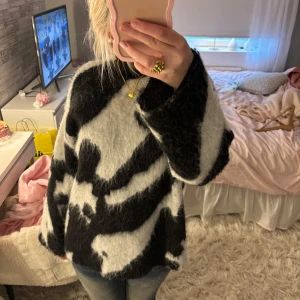Fluffig svartvit stickad tröja från Stockh LM Studio - Säljer en supermjuk och fluffig stickad tröja från Stockh LM Studio. Tröjan har ett svartvitt mönster som påminner om zebra och är perfekt för kyligare dagar. Långärmad och oversized passform för en avslappnad look. Använd ett fåtal gånger💘