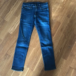 Blå skinny jeans från Polo Ralph Lauren - Säljer ett par blå skinny jeans från Polo Ralph Lauren, modell Eldridge Skinny. Klassisk femficksdesign med dragkedja och knapp framtill. Snygg tvätt och smal passform som sitter tajt hela vägen ner.