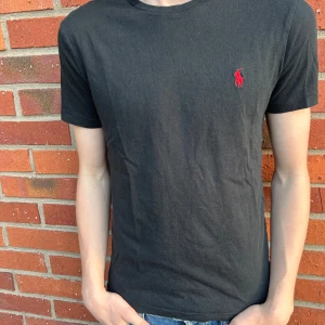 Svart t-shirt från Ralph Lauren - Svart t-shirt med röd häst från Ralph Lauren, storlek S och modellen är 180 cm därför lite liten, perfekt nu till sommaren och våren!