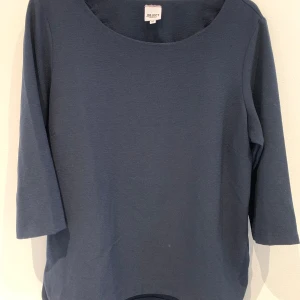 Mörkblå topp från Object - En stilren mörkblå topp från Object med rund halsringning och trekvartsärm. Perfekt för en enkel och clean look. Materialet känns mjukt och bekvämt mot huden.