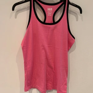 Rosa linnetopp från WA Action Sports - Säljer en sportig rosa linnetopp från WA Action Sports med svarta kanter. Perfekt för träning eller varma dagar. Modellen är ärmlös och har brottarrygg för extra rörelsefrihet.