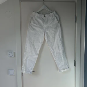 Vita linnebyxor med resårmidja - Säljer ett par vita linnebyxor i storlek XS med resår i midjan och knappstängning. Byxorna har raka ben och sidfickor, perfekta för varma dagar. Lätta och luftiga i materialet.