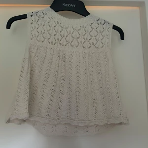 Vit spetslinne från Zara - Supersöt vit ärmlös topp från Zara i spets med v-ringning och fina virkade detaljer. Perfekt för varma dagar och ger en romantisk känsla till outfiten. Luftig och lätt att matcha med jeans eller kjol. lite kortare i magen