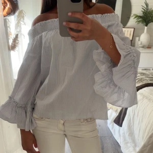 Offshoulder blus med volangärm - Snygg offshoulder blus i ljusblått och vitt med tunna ränder. Blusen har vida volangärmar och en lös passform. Perfekt för vår och sommar🤍🌊🫧☀️
