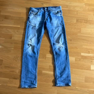 Replay jeans - Säljer ett par blå jeans från Replay Grover med slitningar. Klassisk femficksmodell med normal passform och raka ben. Perfekta för en laidback stil.