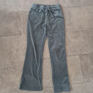 Grå mjukisbyxor från Gina Tricot - Mysiga grå mjukisbyxor från Gina Tricot med dragsko i midjan och raka ben. Byxorna har två bakfickor och är tillverkade i ett mjukt, fleeceliknande material. Perfekta för en avslappnad stil.