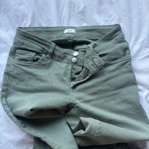 Gröna bootcut jeansbyxor - Säljer ett par gröna jeansbyxor med bootcut-modell. Byxorna har klassisk femficksdesign, dragkedja och dubbla knappar i midjan. Snygga detaljer på bakfickan och passar perfekt till vardagslooken.