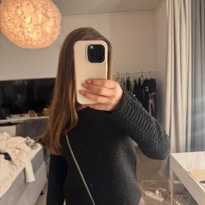 Svart quiltad tröja med dragkedja - Snygg svart quiltad tröja med dragkedja framtill. Perfekt för en stilren look och passar bra till både jeans och kjol. Tröjan har långa ärmar och en modern design.