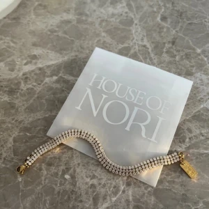 Glittrigt armband från House of Nori - Elegant armband från House of Nori med glittrande stenar och guldfärgade detaljer.  Är vattentåligt så du kan använda det hela tiden 😍 har tyvärr tappat två stenar plus jag har tagit av några ”ringar”, därför det billiga priset 🌸 