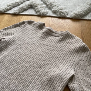 Beige ribbad tröja - Säljer en stilren beige ribbad tröja med långa ärmar. Perfekt för en avslappnad look. Tröjan är från John Henric men tyvärr har lappen i nacken lossnat, hör av er vid frågor 