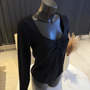 Svart ribbad topp med knyt - Snygg svart ribbad topp med långärmad design och en knytning framtill. Perfekt för en stilren look. Passar bra i m/l storlek. Jag rekommenderar den varmt.🌸👌