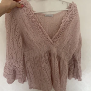 Rosa spetsblus från Zara - Säljer en rosa spetsblus från Zara med v-ringning och omlott-design. Blusen har trekvartsärmar med volangdetaljer och ett vackert spetsmönster. Perfekt för en somrig look! Vet ej storlek men typ m. 20kr
