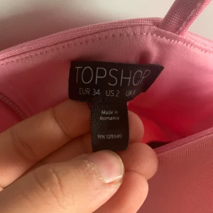 Rosa korsettopp från Topshop - Säljer en söt rosa korsettopp från Topshop med smala axelband. Perfekt för en somrig look eller en utekväll. Toppen har en stilren design och är tillverkad i ett mjukt material.