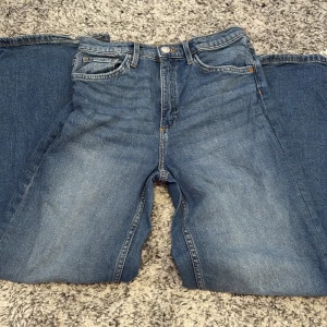 Blå jeansbyxor står ingen storlek  - Säljer ett par klassiska blå jeansbyxor med fem fickor och knappgylf. De har en rak passform och är tillverkade i slitstarkt denimtyg. Perfekta för en avslappnad stil.