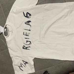 Vit t-shirt från Maison Margiela - Säljer en vit t-shirt från Maison Marigela. T-shirten har en klassisk rund hals och är kortärmad. Perfekt för en stilren och modern look. Ovanligt efttertrakftad tshirt. Aldrig använd. Skriv till mig vid mer frågor🤩💫