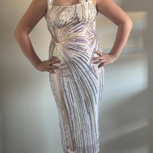 Glittrig axelbandslös klänning - Säljer en fantastisk glittrig klänning med paljetter i guld och silver. Den är axelbandslös och har en tight passform som framhäver figuren. Perfekt för festliga tillfällen!