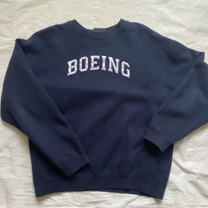 Mörkblå sweatshirt från Oarsman - Säljer en mörkblå sweatshirt från Oarsman med texten 'BOEING' i vitt på framsidan. Tröjan är tillverkad i en bomulls- och polyesterblandning och är oversized