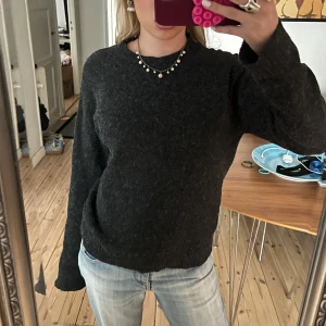 Svartgrå stickad tröja - Säljer en mysig svartgråa stickade tröjan med långa ärmar. Perfekt för kyligare dagar och enkel att matcha med olika outfits. Tröjan har en klassisk design och är ett måste i garderoben.