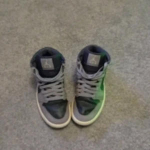 Grå Nike Air Jordans - Säljer ett par grå Nike Air Jordans med snörning och klassisk design. Skorna har en vit sula och en svart swoosh på sidan. Perfekta för dig som älskar sneakers med stil.