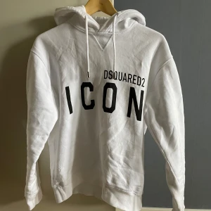 Vit hoodie Dsquared2 - Säljer en Dsquared2 ICON hoodie i storlek M. Mycket fint skick de ända anmärkningsbara är ett av snörenas botten har lossnat som man ser på sista bilden, annars perfekt! Hoodien är självklart äkta och e-kvitto finns, nypriset är ca 4 200kr men jag säljer den för 599kr!