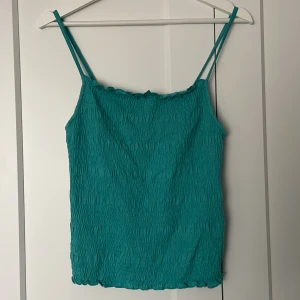 Turkos linnetopp från & Other Stories - Säljer en turkos linnetopp från & Other Stories i storlek M. Toppen har smala axelband och en lätt rynkad textur som ger en fin detalj. Perfekt för varma dagar eller som ett lager under en kavaj.