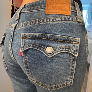 Blåa jeans från Levi's - Säljer ett par blå jeans från Levi's med en bootcut passform. De har en slitning på ena benet och en knappgylf. Även snygga fickor!! Skriv vid funderingar 🥰🥰🥰