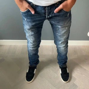 Dondup George - Snygga blå jeans från dondup George med en sliten look och ljusa detaljer. De har en klassisk femficksdesign och en dragkedja framtill. Perfekta för en avslappnad stil. W30 L30 Inges defekter på jeansen. Hör av dig vid frågor eller funderingar.