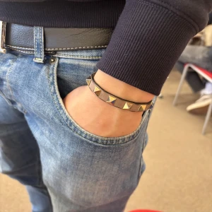 Beige Valentino armband - Snygg beige valentino med med guldfärgade nitar. Perfekt accessoar för att ge din outfit en cool touch. Armbandet har ett justerbart spänne för bästa passform. Skick ungefär 8/10. Självklart äkta, tveka inte med att skriva!