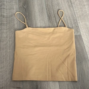 Beige linnetopp - Säljer en enkel och stilren beige linnetopp från Gina Tricot i storlek XS. Toppen har tunna axelband och rak skärning, perfekt att matcha med jeans eller kjol. Materialet känns mjukt och stretchigt mot huden. ALDRIG ANVÄNT!!