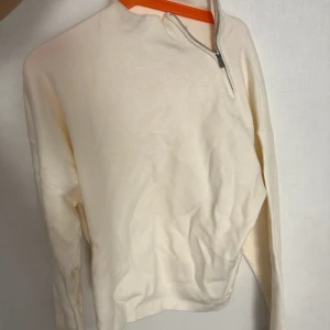 Vit stickad tröja med half zip från MNG - Säljer en stilren vit stickad tröja från MNG i storlek XS. Tröjan har lång ärm, ribbade muddar och en snygg half zip-dragkedja vid halsen. Perfekt för lager-på-lager och enkel att matcha med jeans eller kjol.