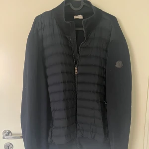 Svart/blå Moncler pufferjacka med dragkedja - Moncler jacka/Hybrid Zip Cardigan/Äkta moncler.  Svart/Blå  cardigan från Moncler med quiltad front och släta ärmar. Perfekt skick,kan uppvisa äkthets bevis. 