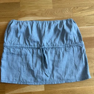 Blå prickig tubtopp från langsåm studio - Supersöt blå prickig tubtopp från langsåm studio med små ljusblå prickar och knytband i midjan. Toppen har en avslappnad passform och är gjord i ett mjukt bomullstyg, perfekt för varma dagar. Enkel att styla med både kjol och byxor. Köpt i Danmark. Står ingen storlek men skulle säga att den kan passa xs-m 🤩