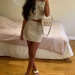 Beige kortkjol med pärldetaljer - Stilren beige kortkjol i manchester med snygga pärldetaljer på fickorna. Kjolen har en rak passform och passar perfekt till en trendig vardagslook. Enkel att matcha med crop tops eller stickade tröjor. Har endast använt den en gång!!!