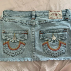True Religion ljusblå jeanskjol - Säljer en ljusblå jeanskjol från True Religion i väldigt bra skick. Dock tvättade ett par gånger så kanten nertill är lite sliten, därav ett väldigt billigt pris för den kjolen. Hör av dig vid frågor💕