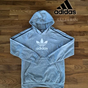 Grå Adidas Hoodie -  Adidas Originals hoodie i storlek S (XL Barnstorlek), grå med vit trefoil-logga och ränder längs ärmarna. Klassisk och sportig design i mjuk bomullsblandning med huva och magficka. I mycket gott skick, knappt använd. Perfekt för vardag, träning eller chill. 📦 Skickas samma dag! Kontakta mig vid intresse. #Adidas #Originals #GråHoodie #Streetwear #Secondhand #Mode #Säljes #Unisex  