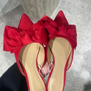 Röda rosett skor Hm - Snygga röda ballerinaskor från H&M med spetsig tå och en stor rosett framtill. Skorna har platt sula och är tillverkade i ett tygmaterial som ger en elegant känsla. Perfekta för dig som vill sticka ut med en färgstark detalj. Så jävla coola med tyvärr inte kommit till användning för mig🥲 storlek 40 men passar även 39