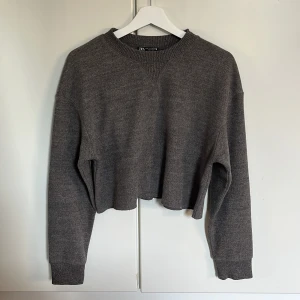 Stickad tröja - Mörkgrå croppad stickad tröja från Zara med rund halsringning och ribbade muddar. Tröjan har en loose passform och långa ärmar, tröjan är i storlek M. 