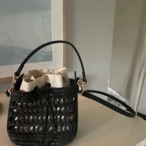 Svart virkad axelväska från hm - Säljer en svart virkad axelväska med snyggt nätmönster och justerbar axelrem. Knappt använd och säljer så jag hittade en annan väska så denna kommer ej till användning.