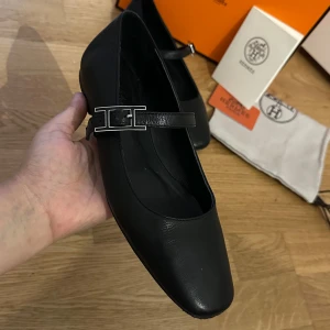 Svarta ballerinas i äkta läder - Stilrena svarta ballerinas  i äkta läder med klassisk .Snygg rund tå och platt sula, perfekt för dig som gillar en tidlös och lyxig look. Kommer med originalbox och dustbag. Använd få gånger 